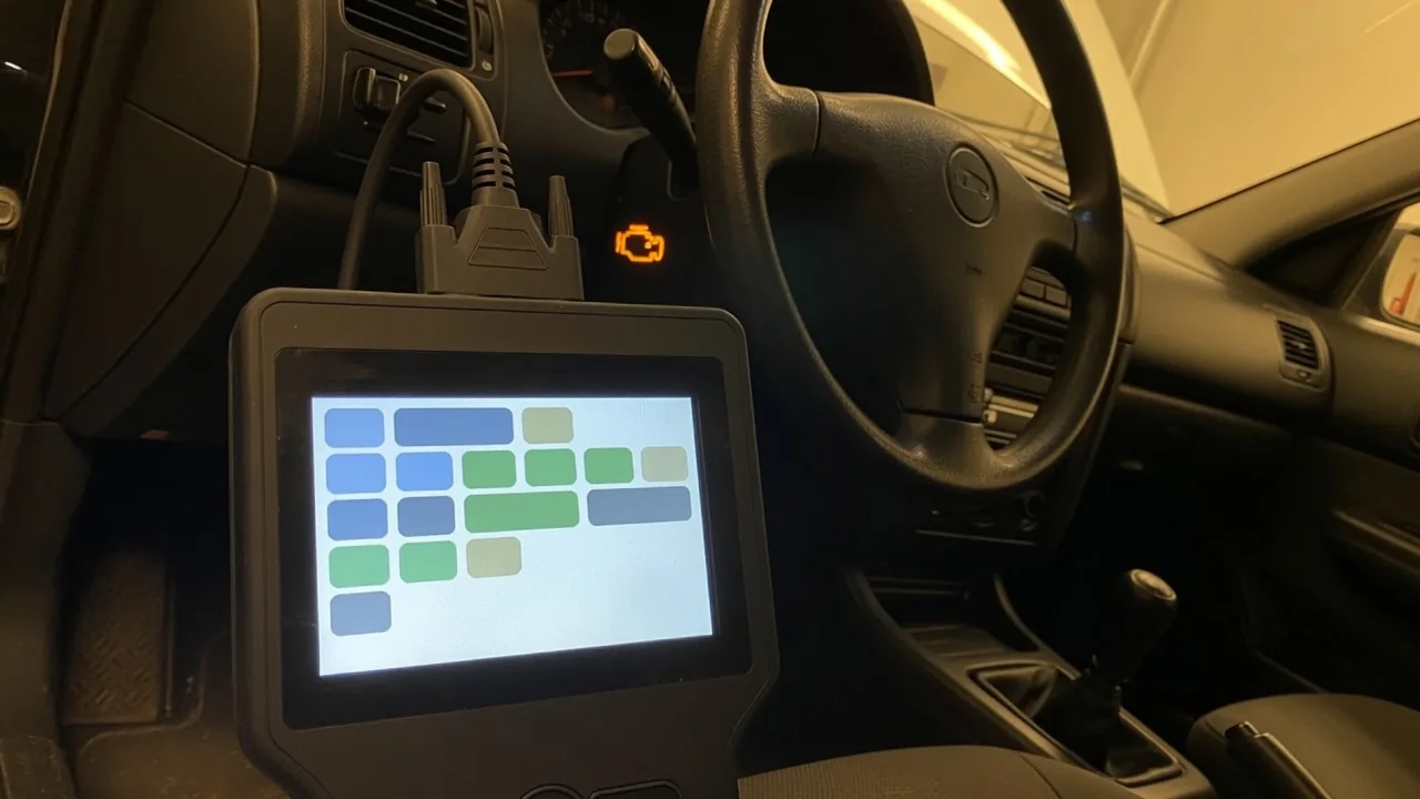 OBD-II scan tool connected under a car dashboard with the check engine light on