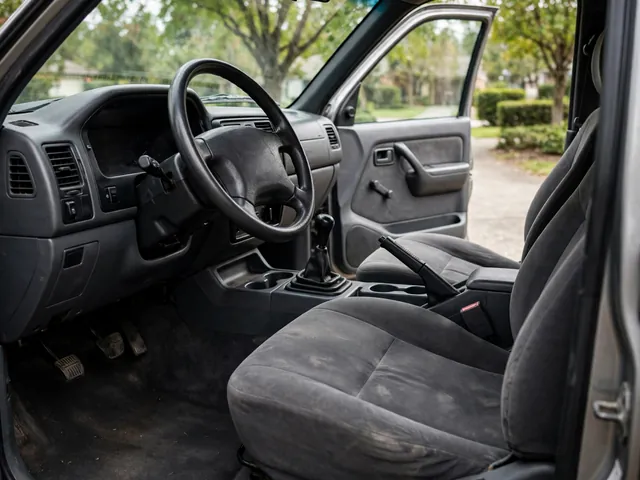 Pickup truck interior showing a manual gearshift, clutch pedal and steering wheel