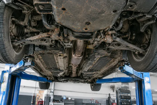 Car undercarriage showing surface rust on exposed metal, with suspension and underbody components visible