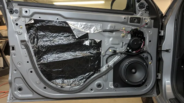 Car door with trim panel off, showing sound deadening material, a mounted speaker and foam strips that reduce rattle