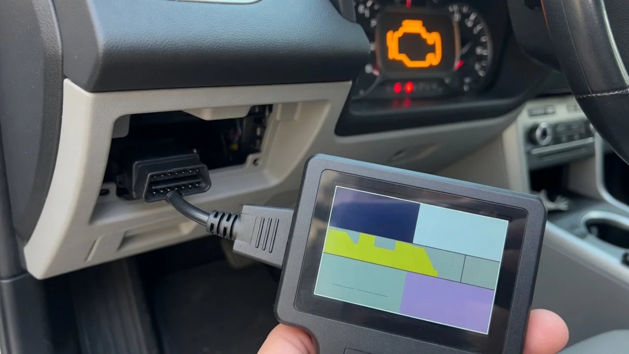 Handheld OBD-II scan tool connected under a car dashboard, showing a diagnostic trouble code reading