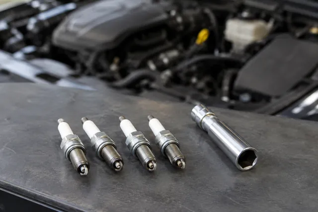 Spark plugs and a spark plug socket arranged on a clean automotive workbench
