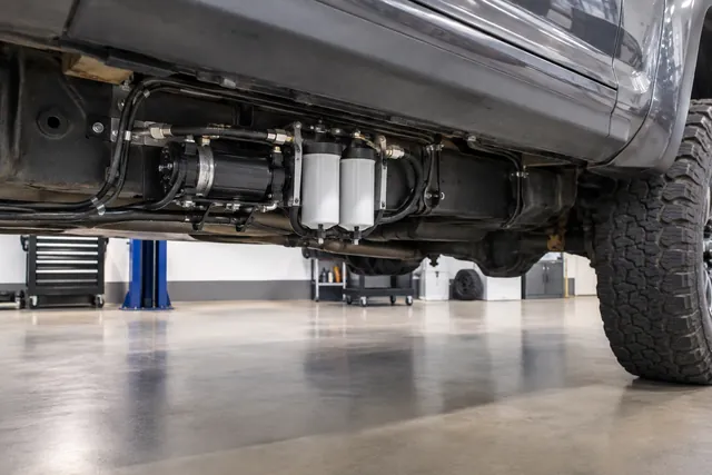 Aftermarket diesel lift pump assembly with filter canisters mounted beneath a truck