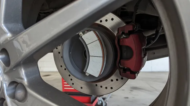Close-up of a car brake rotor and caliper with a new ceramic brake pad, seen through an alloy wheel