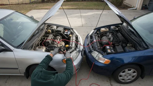 Two cars with hoods open and jumper cables connected, a gloved hand attaching the black clamp to an engine ground point