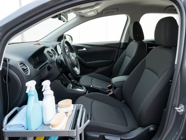 Interior detailing bottles, brushes, and microfiber towels arranged beside a clean car cabin.