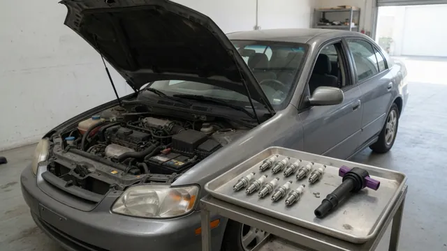 Spark plugs and an ignition coil arranged beside a parked vehicle's engine bay
