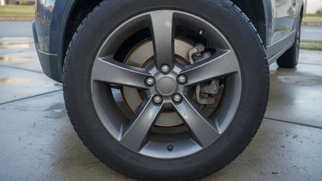 Close-up of a compact SUV's front brake rotor and caliper seen through the wheel, with light surface rust on the rotor