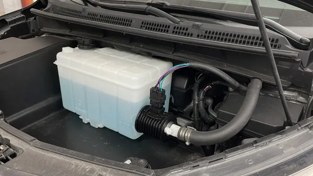 Windshield washer reservoir and electric pump with a hose leading toward the windshield spray nozzles