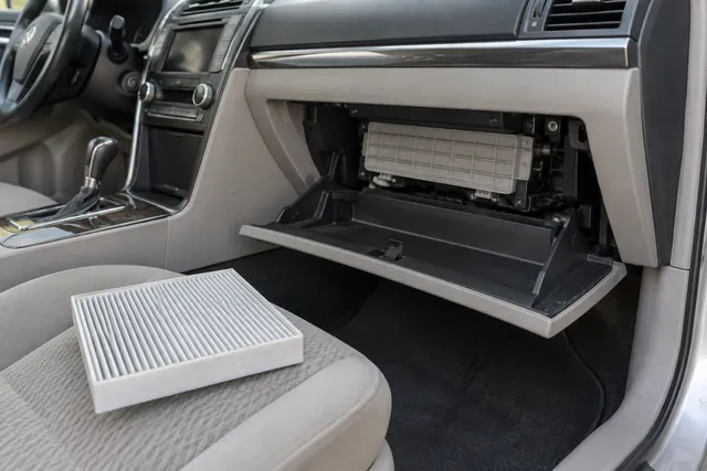 Passenger glove box area showing access to a Toyota Camry cabin air filter housing