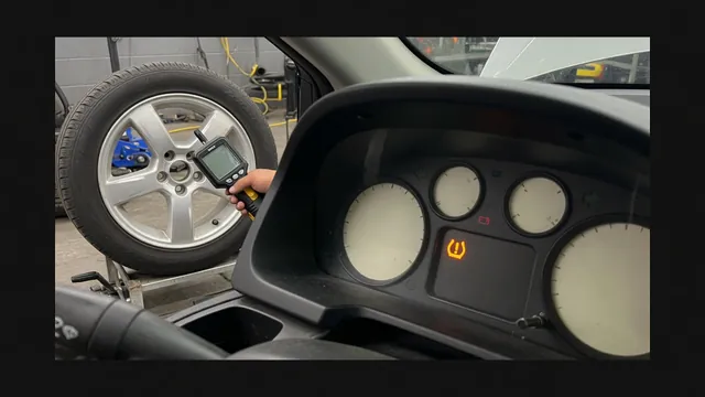 Car dashboard showing a TPMS fault warning and service message with a technician's tire pressure sensor tool near a wheel