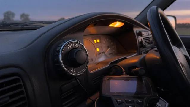 Truck dashboard with a 4WD selector knob, warning lights on, and an OBD-II scan tool plugged in