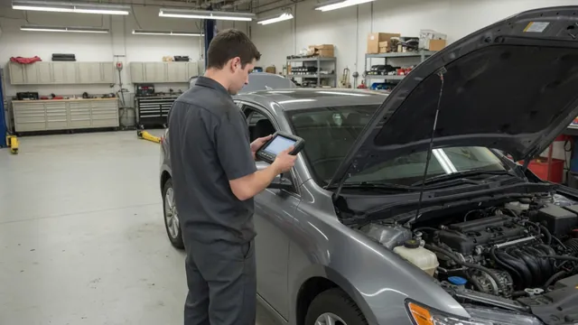Technician reviewing diagnostic scan data beside an open engine bay