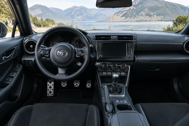 Manual gear shifter and three pedals inside a Toyota passenger car