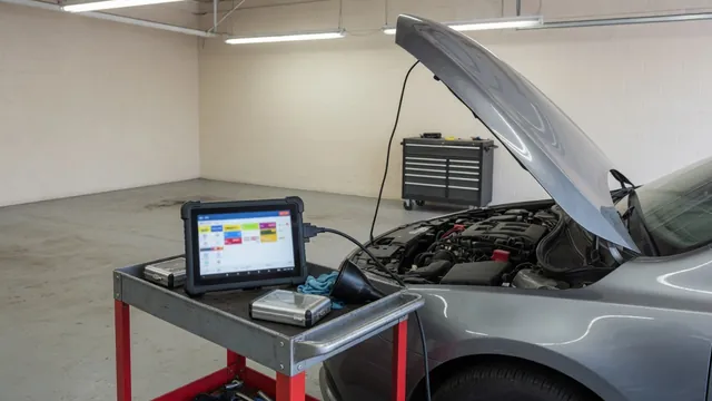 Diagnostic scanner beside a vehicle with its hood open in an automotive service bay