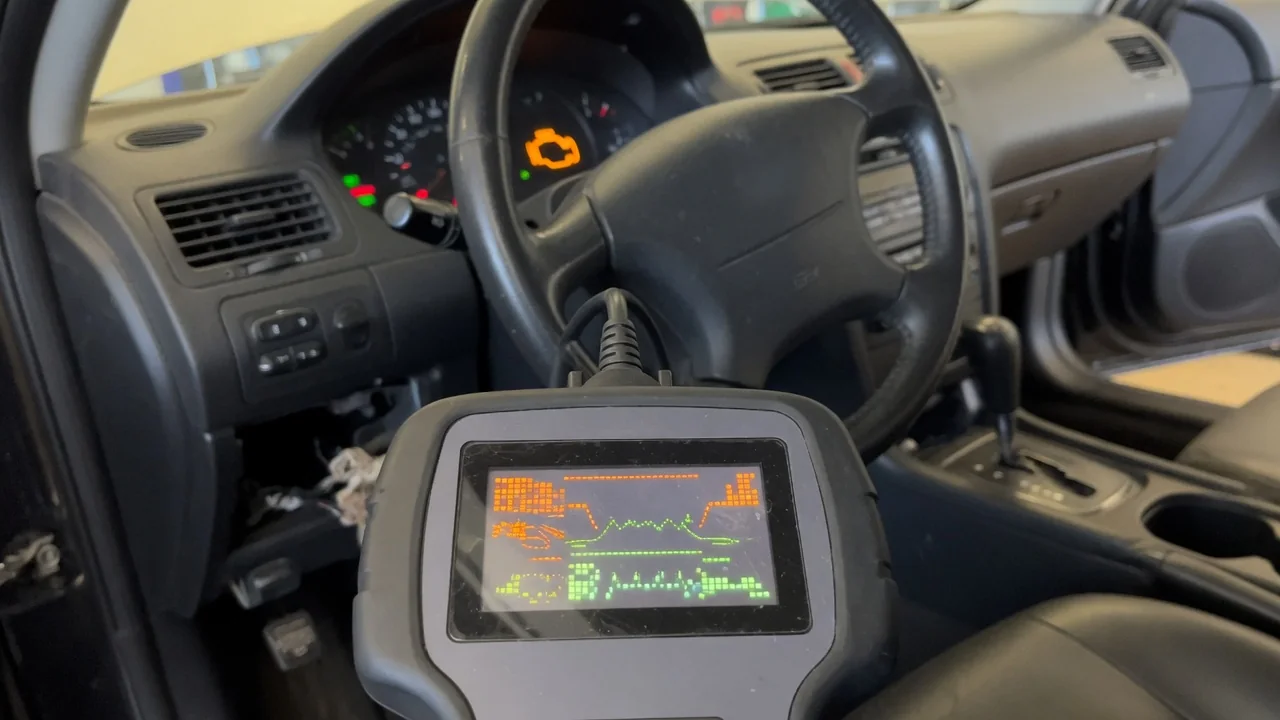 OBD-II scan tool plugged in under a car dashboard to read a trouble code, with the check engine light on