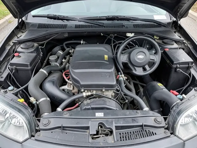 Heater hoses and coolant connections near the firewall in a car engine compartment.