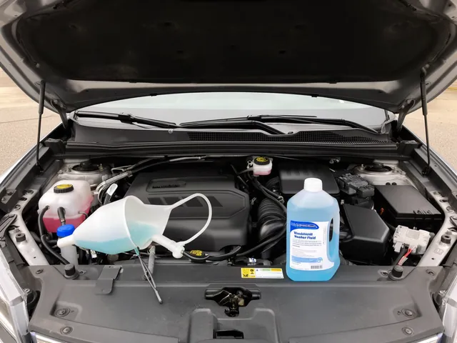 Windshield washer reservoir beside labeled automotive washer fluid and a clean funnel