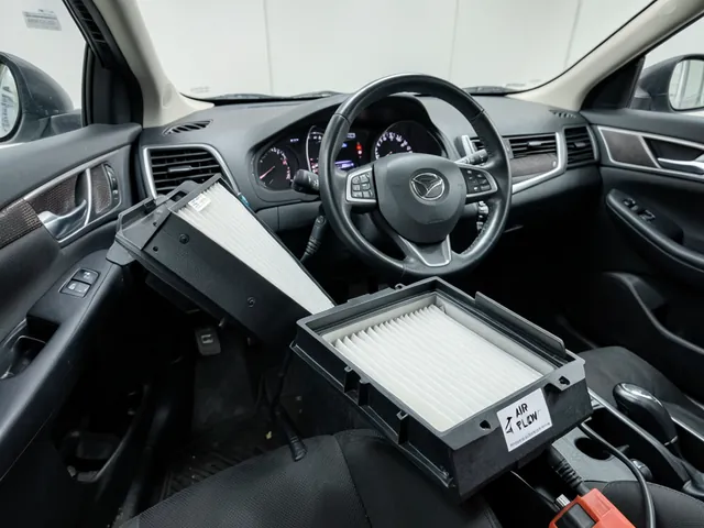 Cabin air filter beside an open filter housing with a visible AIR FLOW arrow on its edge