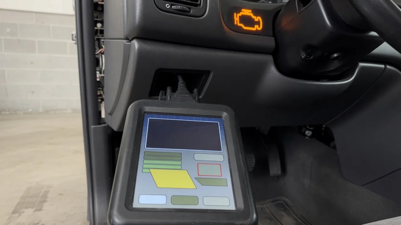 OBD-II scan tool connected under a car dashboard showing a trouble code, with a check engine light glowing in the background
