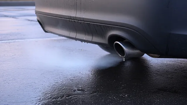 Water droplets beneath a car’s tailpipe on a cool morning outdoors
