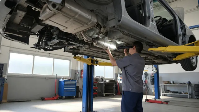 Technician inspecting a vehicle’s exhaust system and catalytic converter on a shop lift