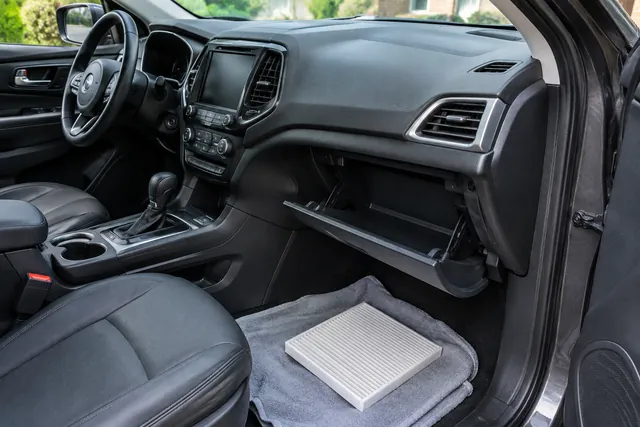 Cabin air filter beside an open Jeep glove compartment, ready for a fitment check