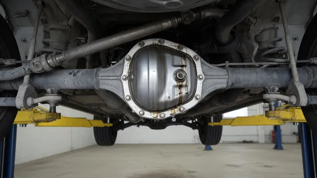Differential housing with visible oil residue near the cover seam on a vehicle raised in a repair shop