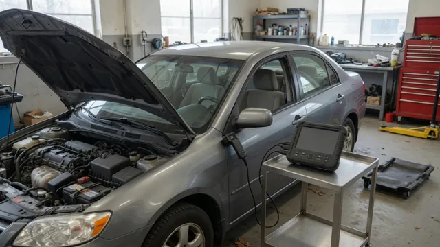 Diagnostic scan tool beside a vehicle with its hood open in an automotive workshop