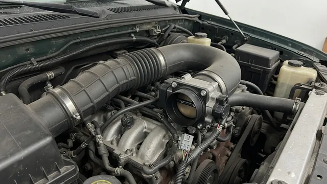 Illustration of a throttle body and intake duct in a Chevy truck engine bay