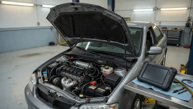 Diagnostic scanner beside a vehicle with its hood open in an automotive service bay