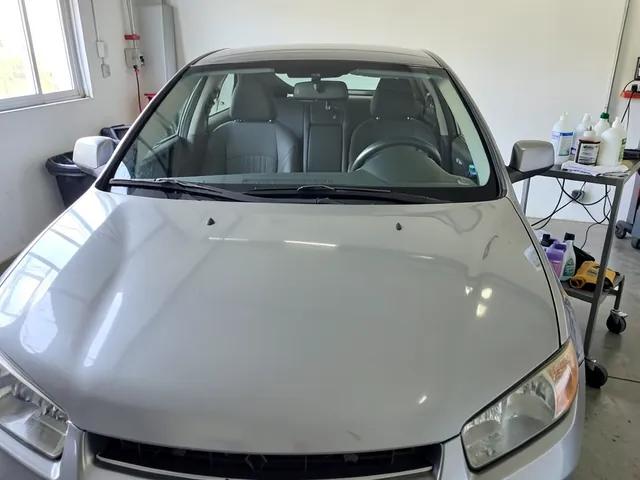 Clean microfiber towels and paint preparation products beside a freshly washed car hood