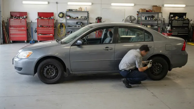 Toyota Camry parked in a service bay with a technician inspecting the wheel area