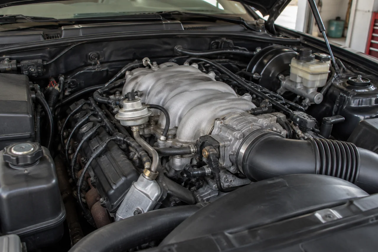 EGR valve and exhaust feed tube near the intake on a full-size sedan V8 engine