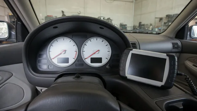 Diagnostic scanner beside a vehicle instrument cluster with a tachometer and speedometer