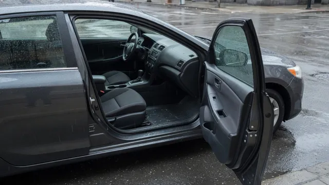 Open passenger door showing a wet floor mat and water droplets along the window