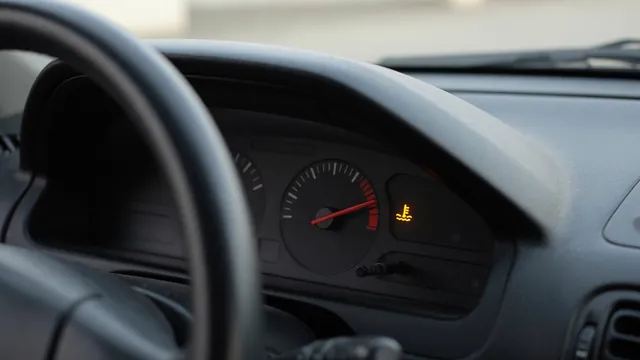 Car dashboard showing a coolant temperature gauge near the hot zone and an illuminated temperature warning