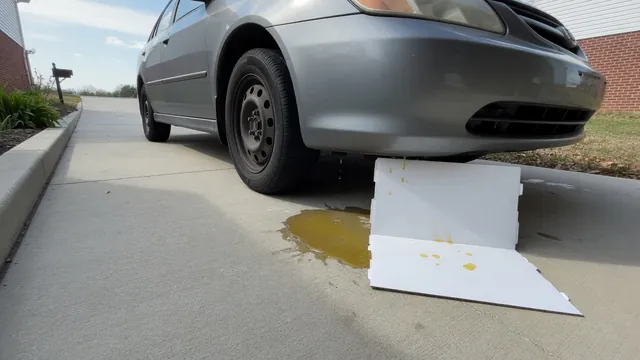 Parked car with a small unidentified puddle beneath the front and clean cardboard positioned to catch drips.