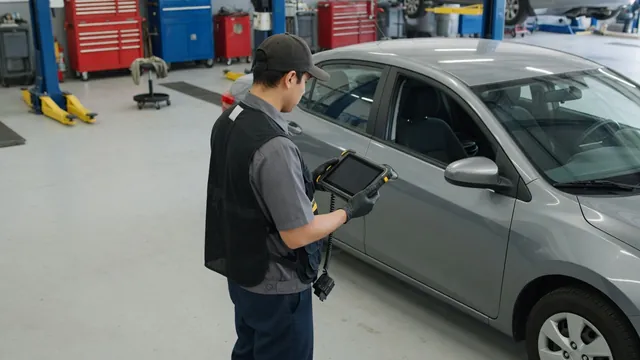 Technician reviewing transmission diagnostic data on a scan tool beside a parked vehicle