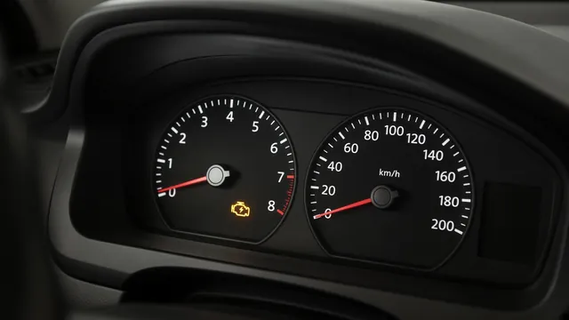 Amber check engine symbol illuminated on the dashboard of a parked car
