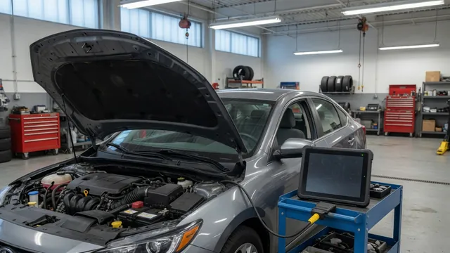 Diagnostic scan tool beside a vehicle with its hood open in an automotive service bay