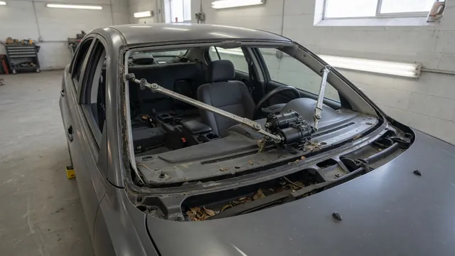 Windshield wiper motor and linkage beneath a removed cowl panel on a parked car