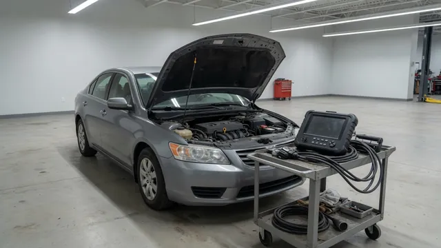 Diagnostic scanner beside a parked car with its engine off and hood open