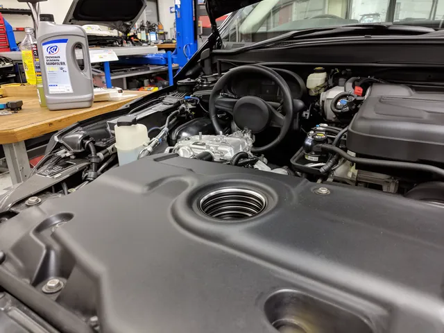 Engine oil filler opening and an unbranded flush product bottle on a workshop bench