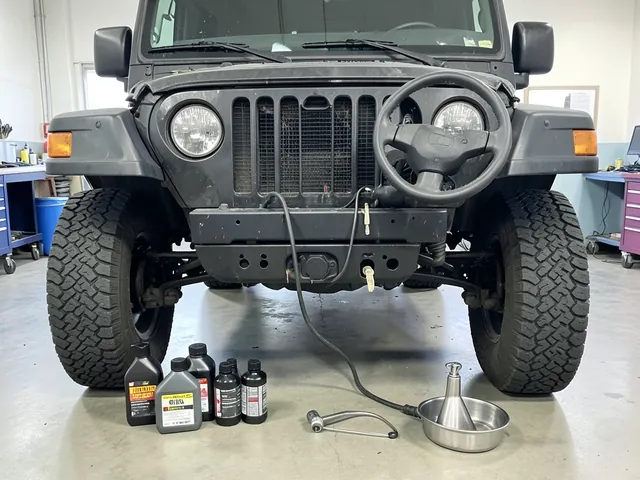 Jeep axle differential housing with sealed gear oil bottles and a fluid transfer pump nearby