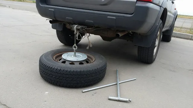 Underbody spare tire hoist, cable retainer, and lowering rods shown with the wheel resting on the ground