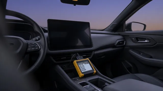 A scan tool plugged into a car's diagnostic port next to a blank infotainment screen, showing a lost communication fault