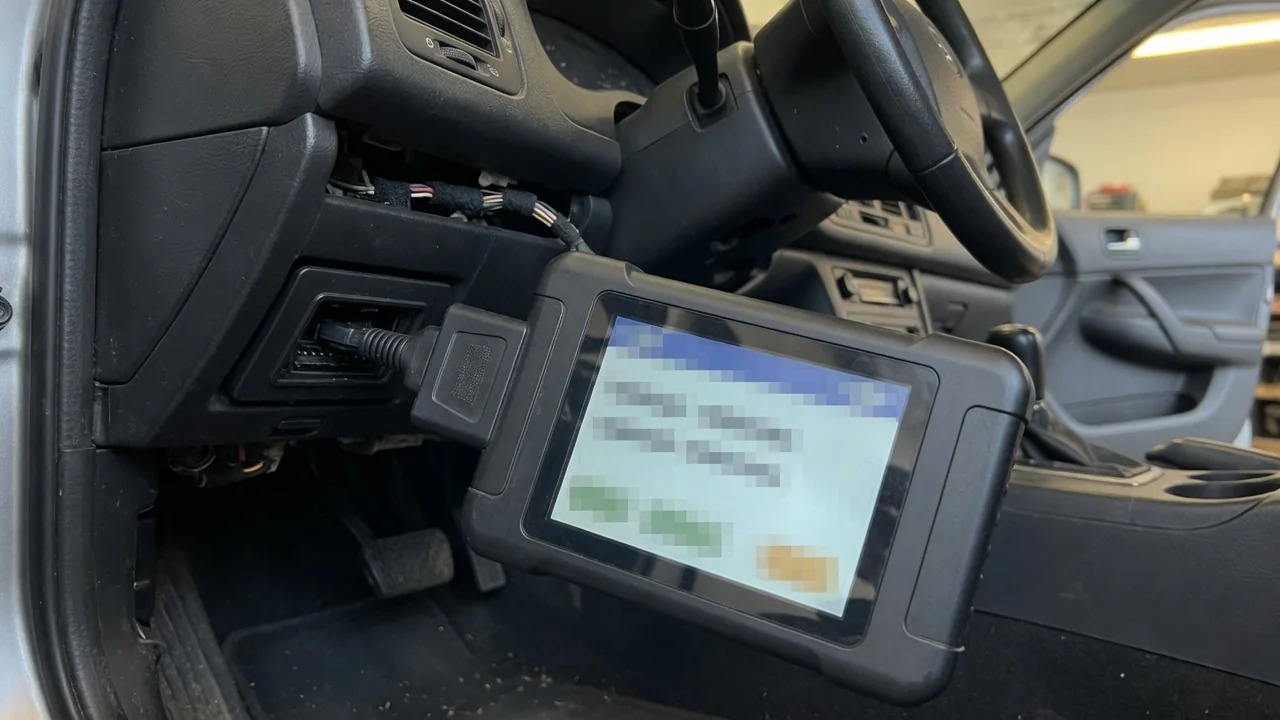 OBD-II scan tool connected under a car dashboard, reading a manufacturer-specific trouble code