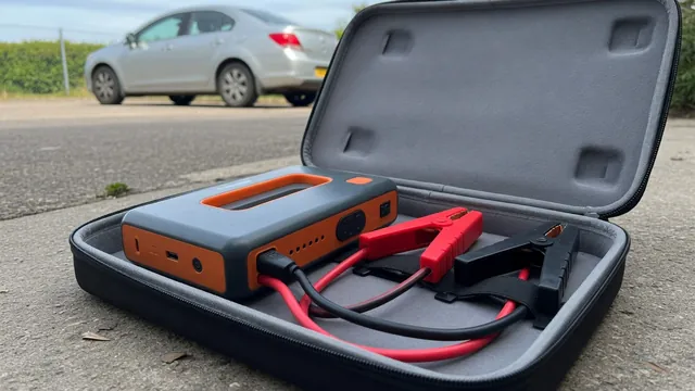 Portable lithium jump starter with insulated red and black clamps stored beside the pack