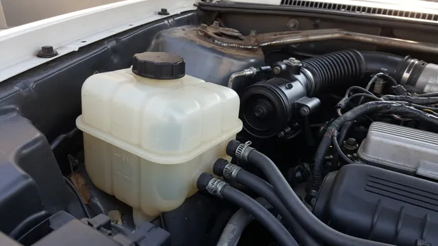 Power steering fluid reservoir with visible minimum and maximum level markings in an engine bay